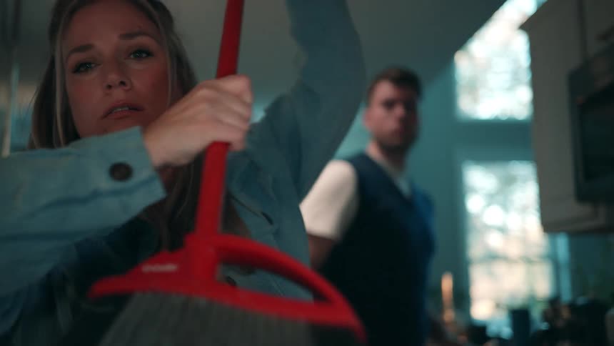 A woman sweeping out stuff in a kitchen