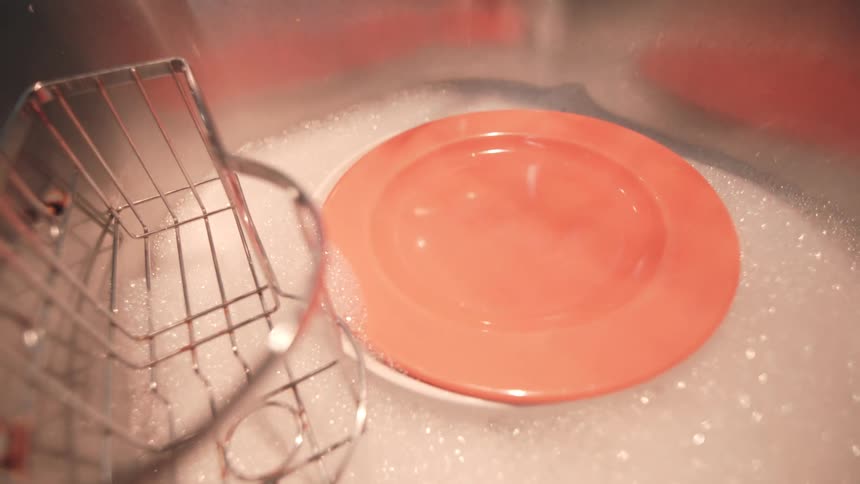 A lot of plates and bowls being placed in a sink