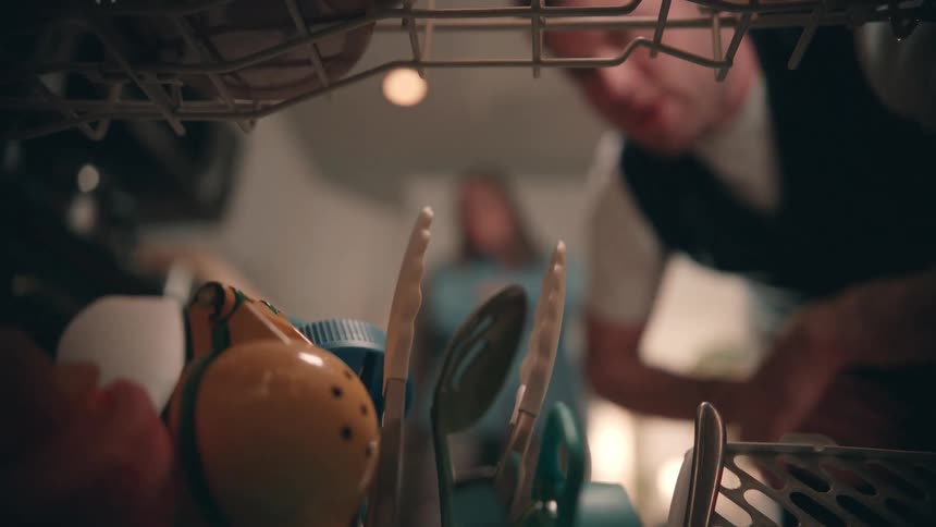 The man is looking inside his dishwasher