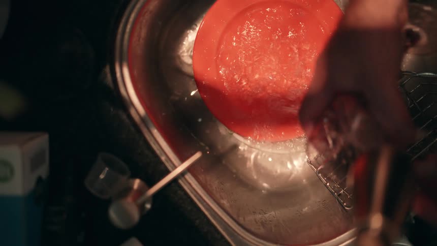 Overhead view of washing a wineglass in kitchen sink