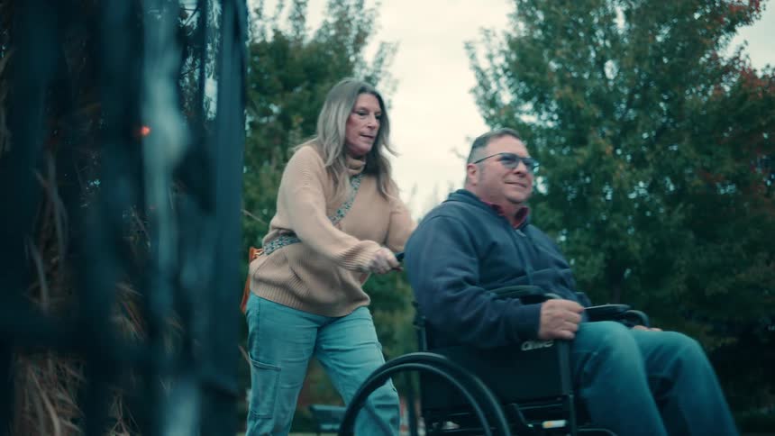 The woman talks with a man in the wheelchair while pushing him