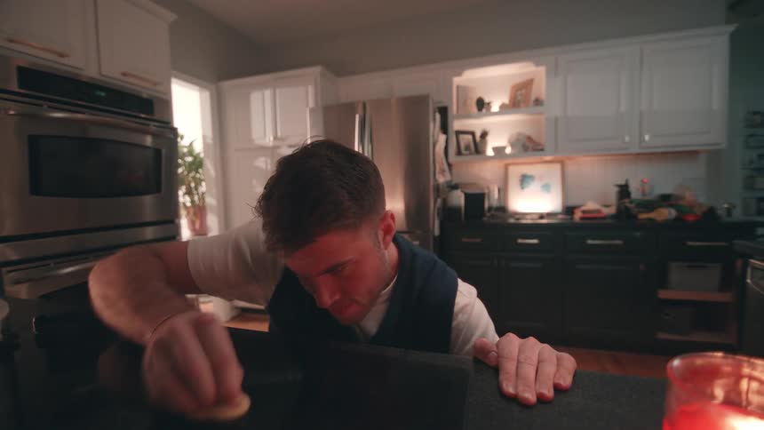 Man cleans the stovetop surface in the kitchen using a sponge