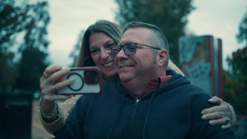 The faces of a man and a woman taking a selfie with a smartphone while they are smiling