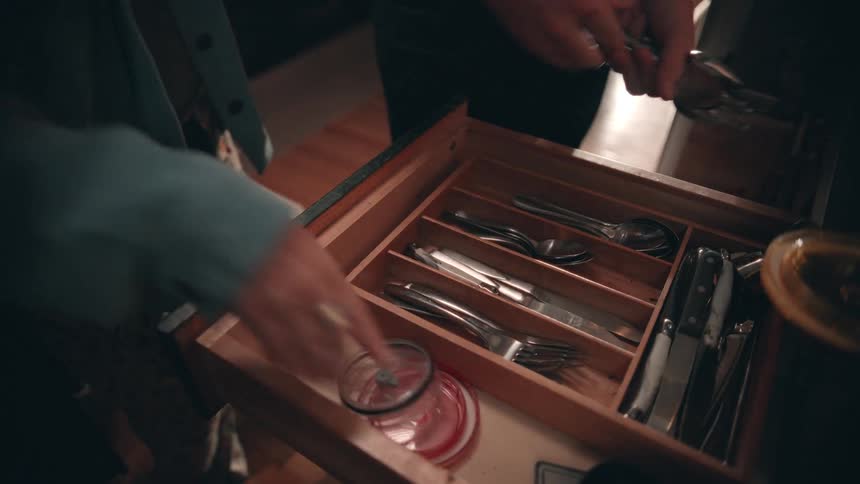Male and female hands arranging cutlery in a drawer indoors during day time
