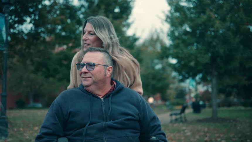The man and woman talk and smile in the park on a windy day