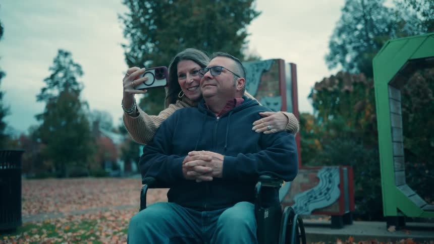 A happy couple takes a selfie together on a cloudy day in a park
