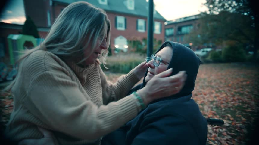 A woman sits in a mans lap to put his hat on
