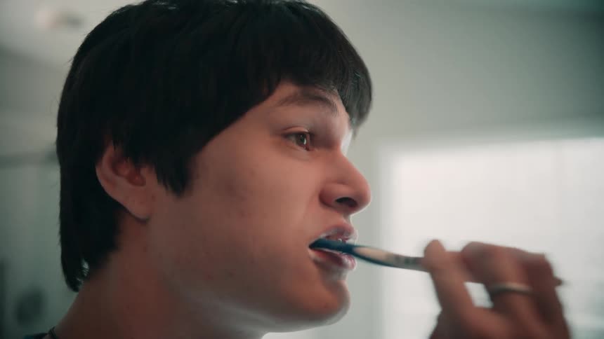 A closeup of a man brushing his teeth in a bathroom