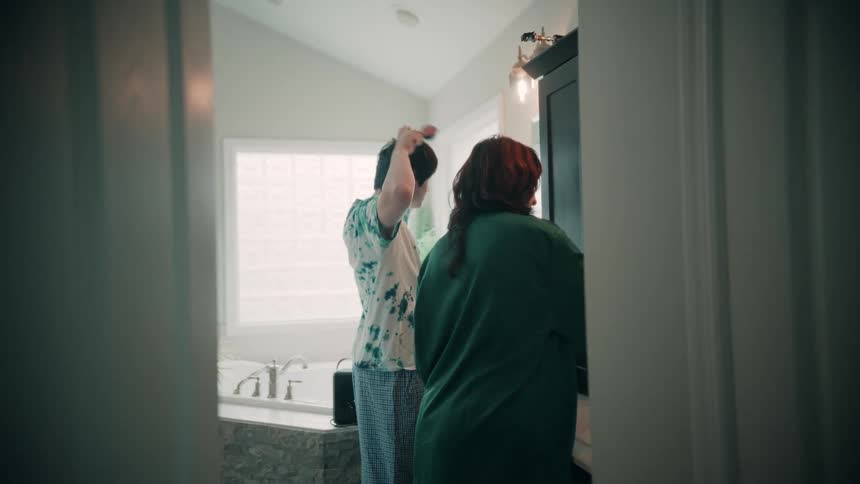 People getting ready in front of the bathroom mirror