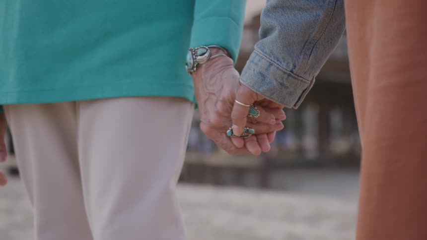 Closeup of an older couple holding hands tightly outdoors