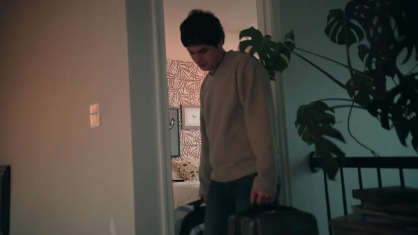 The man carries the luggage out of the room