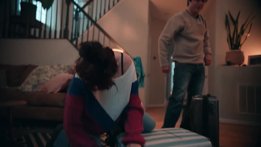 The man and woman zipper their luggage closed