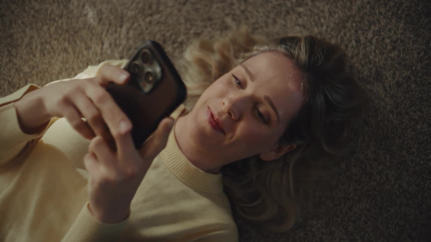 Teenage girl lying on the floor texting on her phone