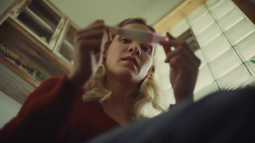 Woman closely examines a pregnancy test inside the bathroom