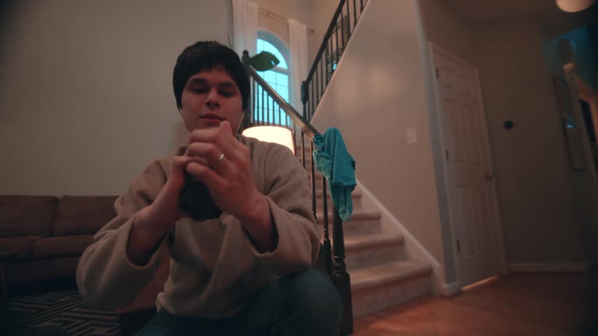 Teenager boy folding clothes and packing them on a suitcase in a living room indoors