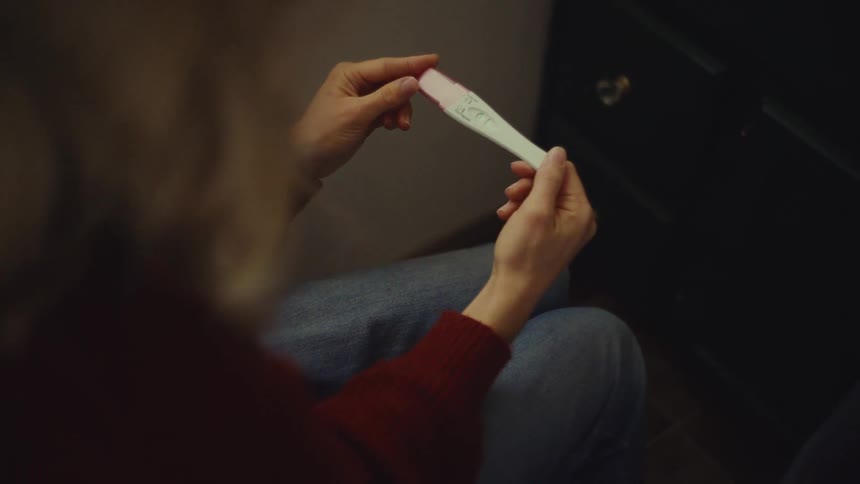 The woman looks at a pregnancy test