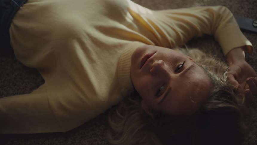 The woman blinks her eyes while laying on the floor