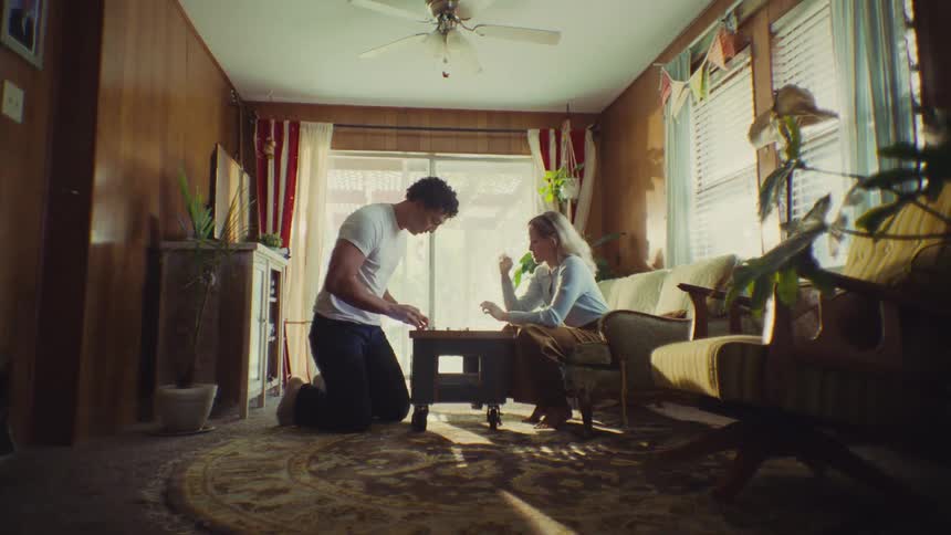 A happy couple plays a dice game on a low table in a retro living room