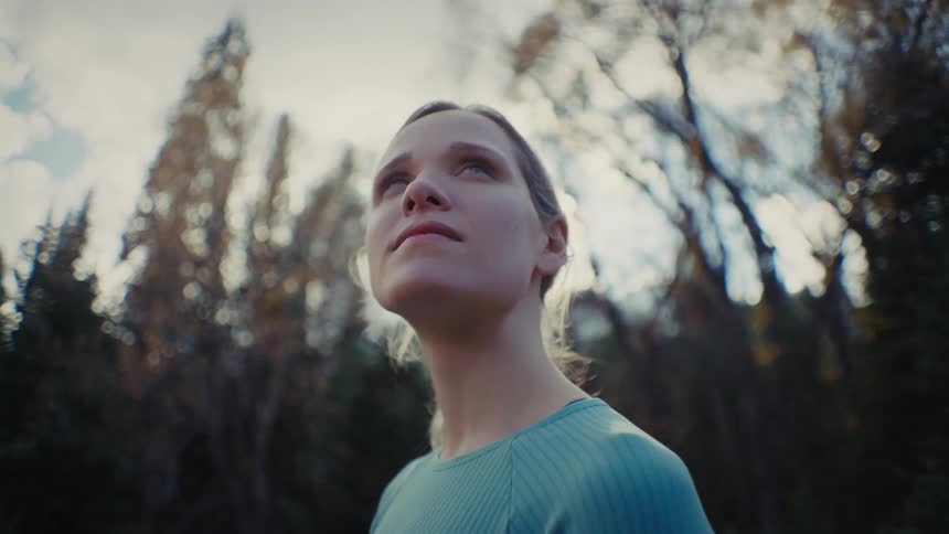 Young woman standing outdoors next to a forest during day time