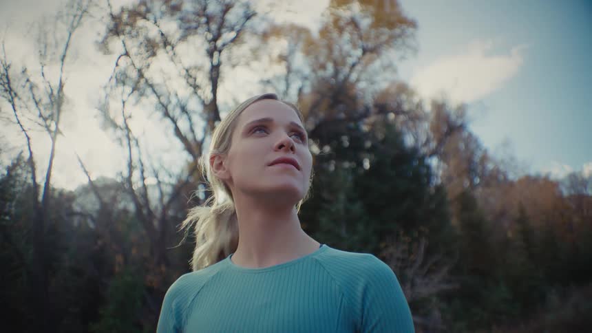 The woman is standing by the forest
