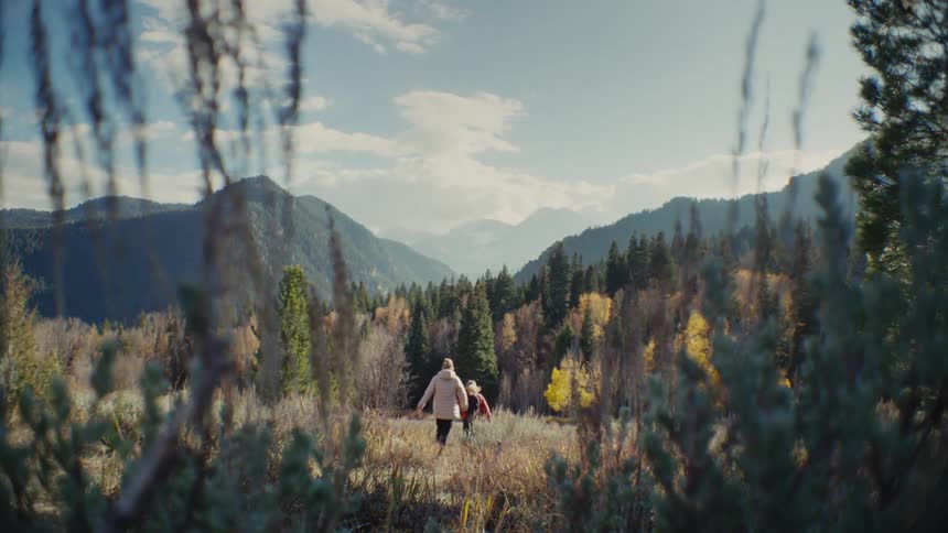 Two teenage girls are out in the woods at midday running after each other and having fun
