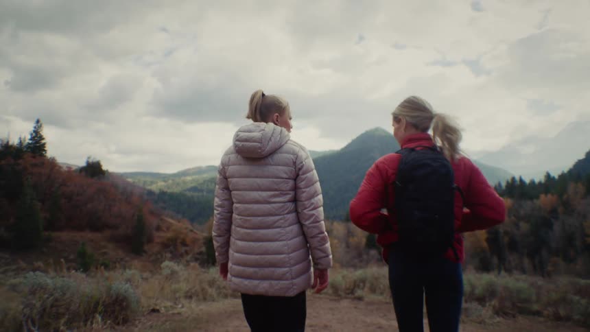 The women talk and hike towards the mountain
