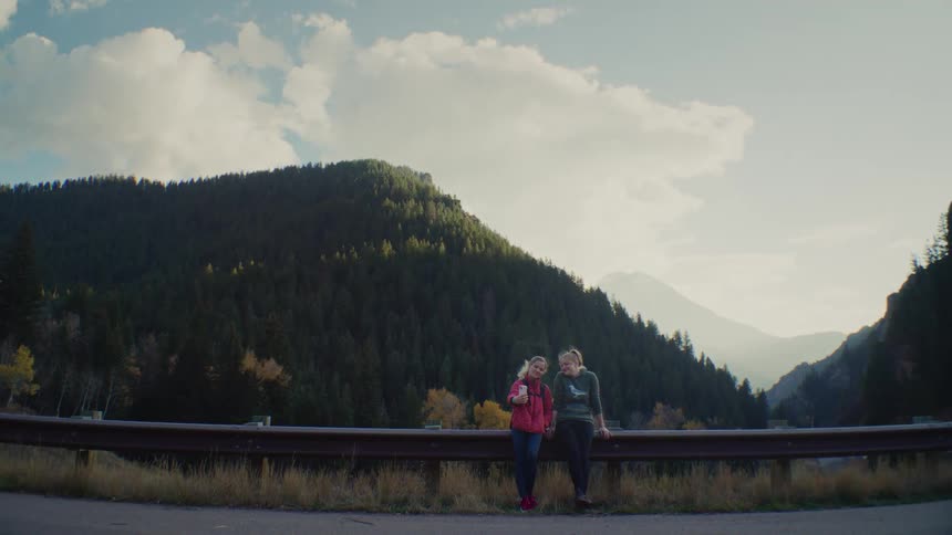 People leaning on the guardrail while enjoying the mountain view at sunset