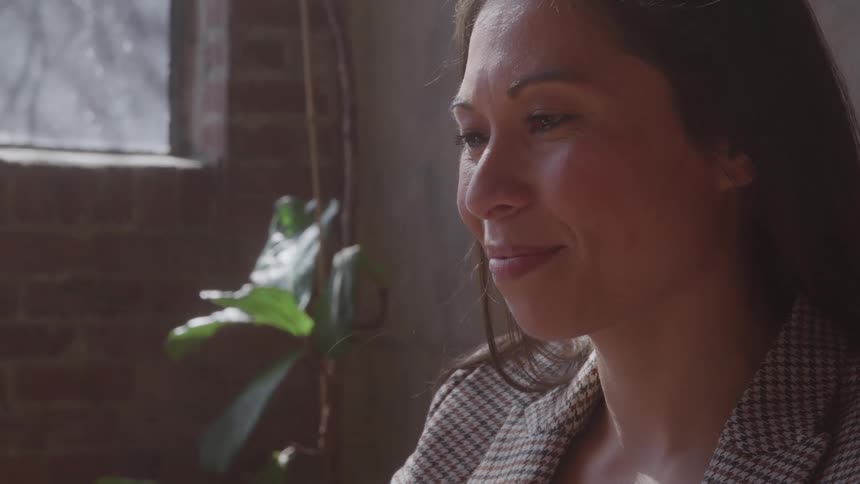 The happy woman is sitting by the window