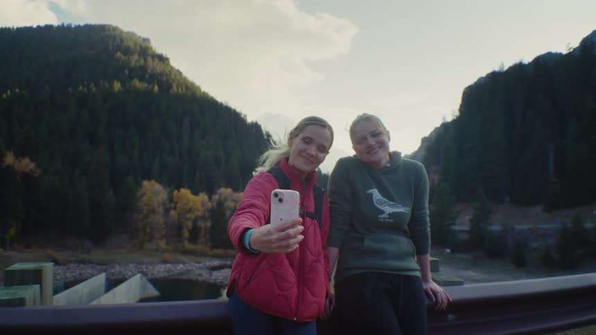Two young girls taking a selfie in the wilderness in the fall