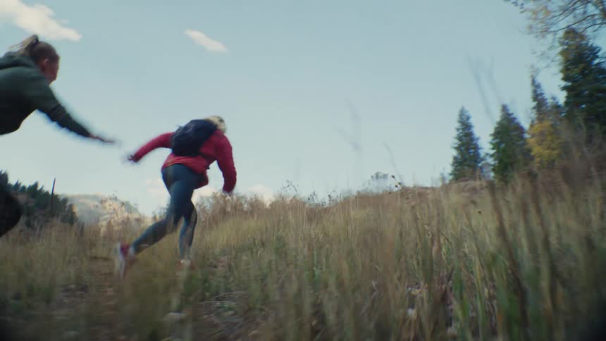 People running along a grassy trail in a mountainous area