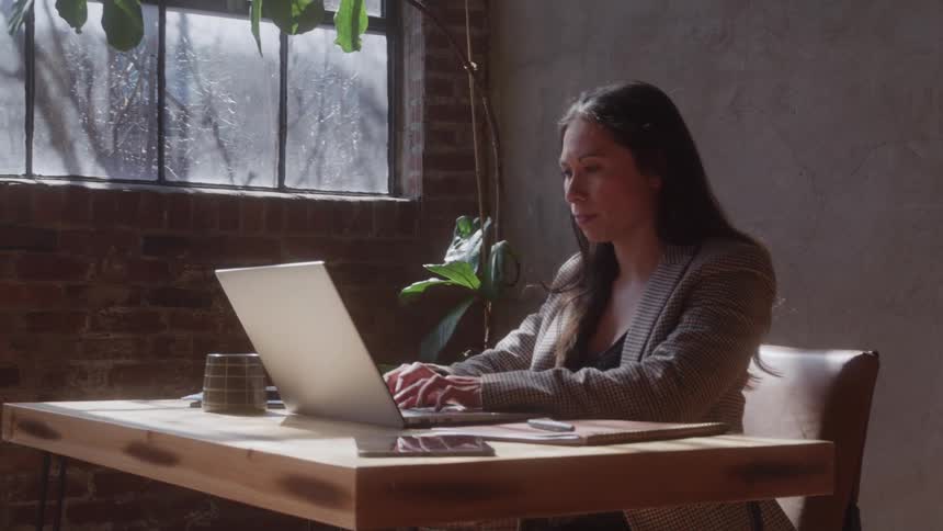 Woman sitting at a desk typing on a laptop computer