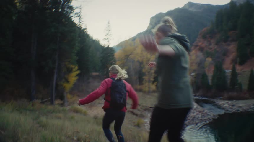 People walking along a narrow trail in a mountainous area surrounded by vegetation