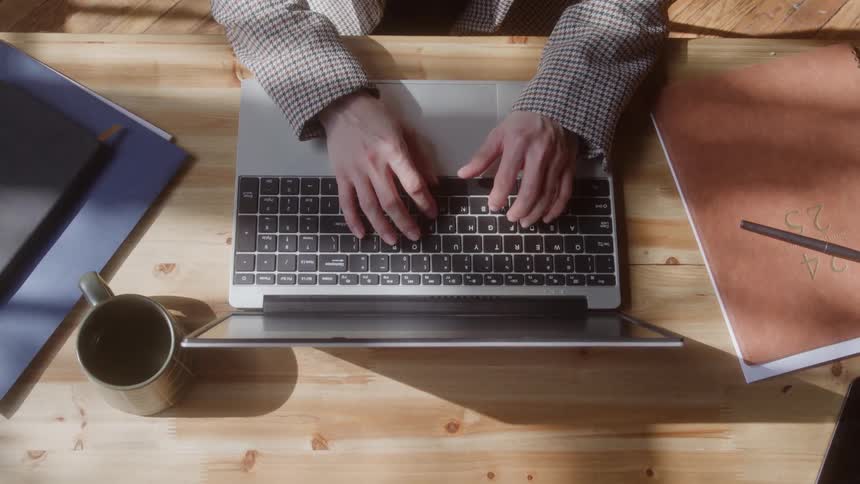 View from above of a womans hands typing on a laptop computer then she closes it and carries it away