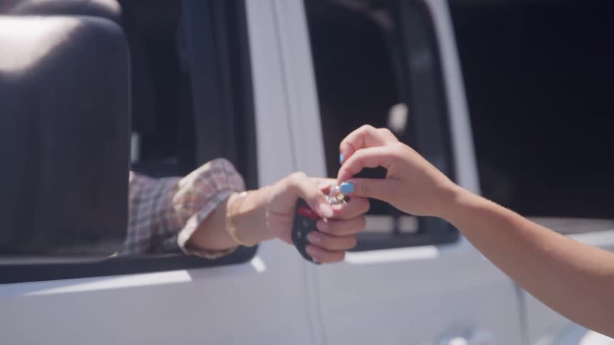 A person handing keys to a person in a truck