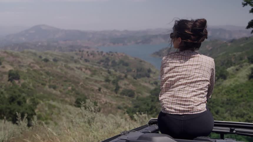 A woman sitting outdoors looking at a lake