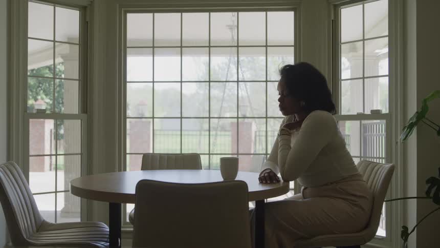 The woman sitting at the table looks out the window
