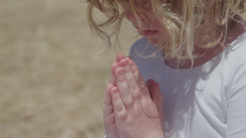 A girl sitting outdoors praying