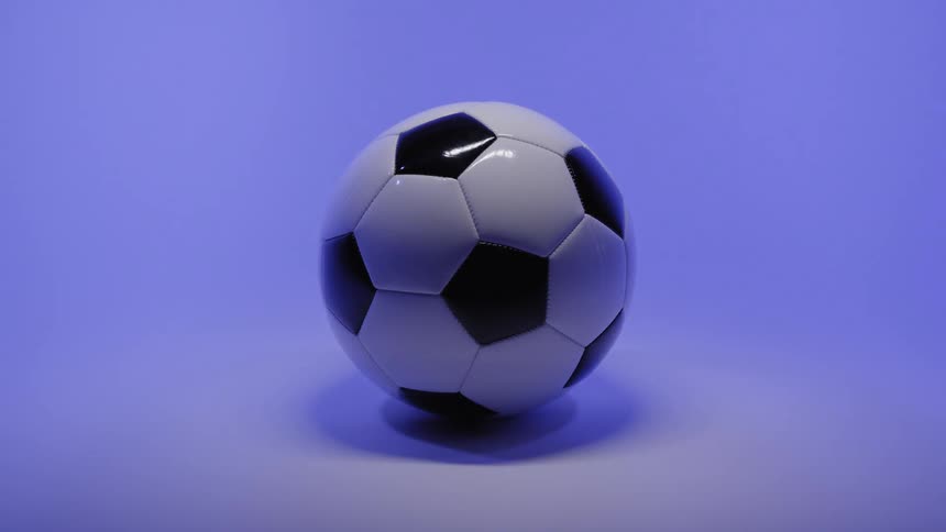 Whiteandblack soccer ball on a lit purple background