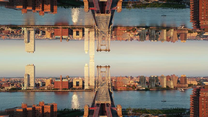 A bridge stretches across a river at midday linking two cities filled with skyscrapers and highrise buildings