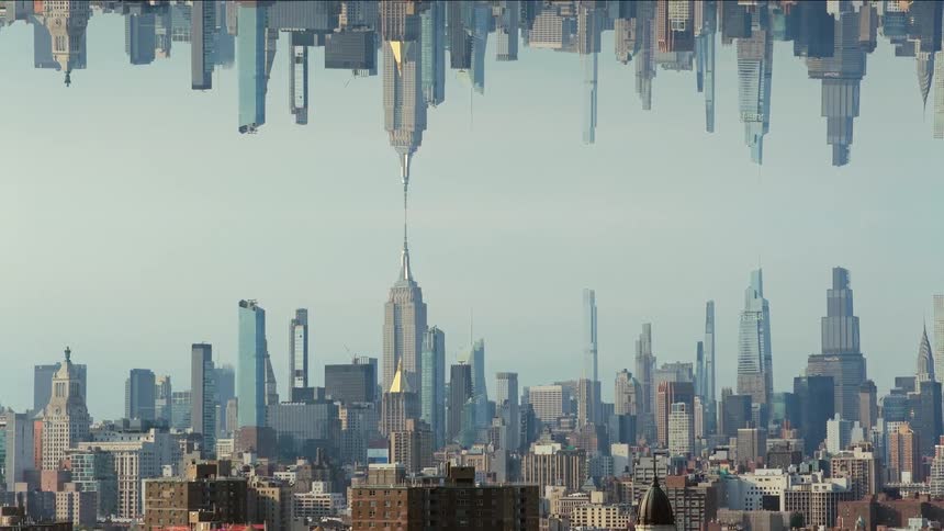 A complex mirrored shot of a dense city skyline featuring tall skyscrapers is reflected vertically against a bright sky creating a surreal architectural composition