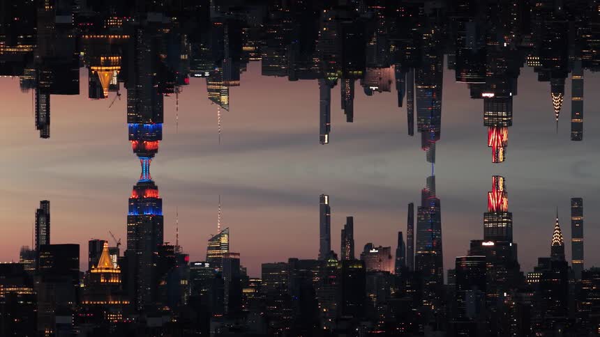 The video features an abstract vertically mirrored image of a skyline likely new york city where the buildings are reflected seamlessly creating an hourglass effectthe most prominent structure appearing to be the empire state building is illuminat