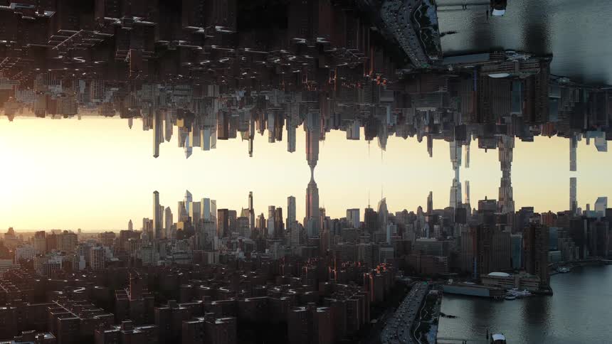 A mirrored view of a dense urban skyline is split by a central bright gap with smokestacks appearing on both sides of the frame