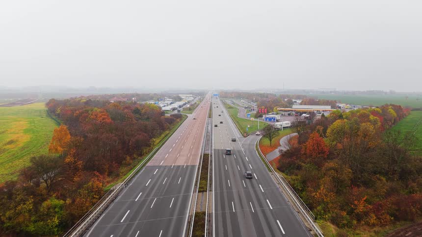 Traffic moves down a highway past an exit with a truck stop