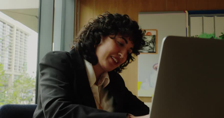 Woman smiles while working on her laptop in the office