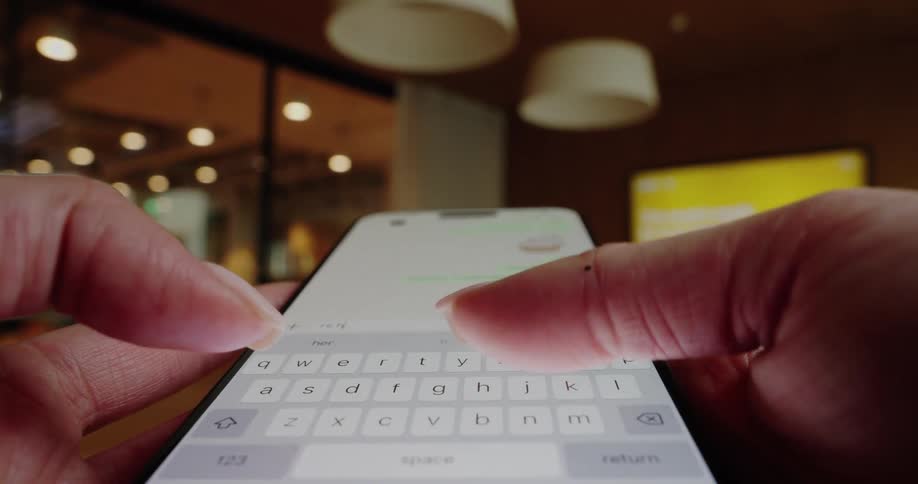 Woman holds her phone with both hands and texts with her thumbs
