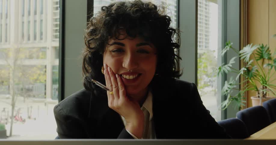 Woman rests her face on her hand while looking at her laptop in the office