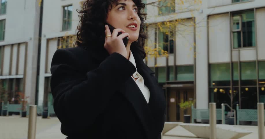Woman walks smiling while talking on the phone in an urban area