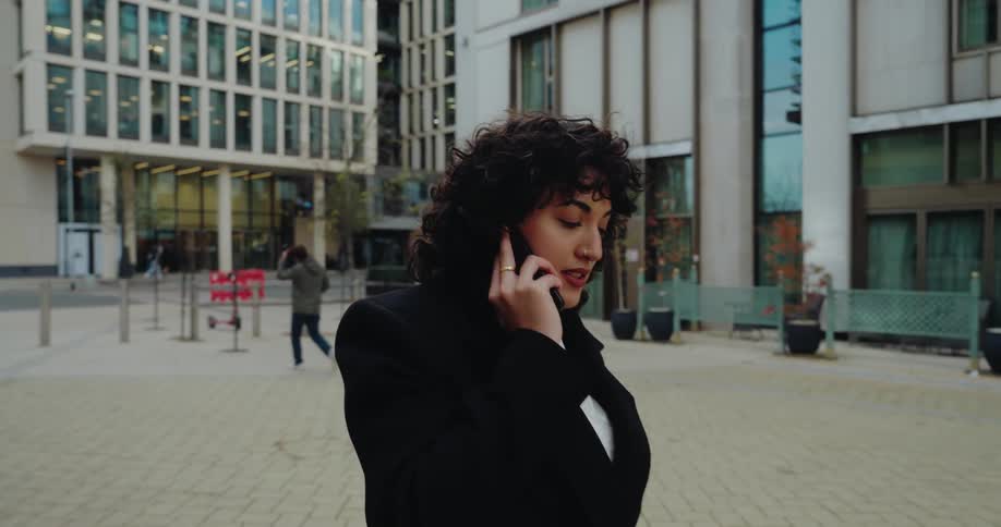 Woman talks on the phone while walking through an outdoor corporate area