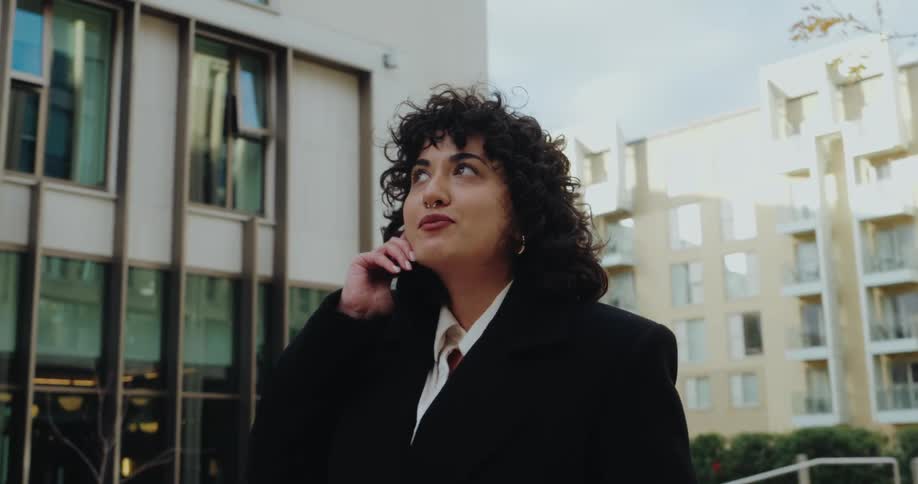 Young woman walking and talking on the phone on a suburban area outdoors during day time
