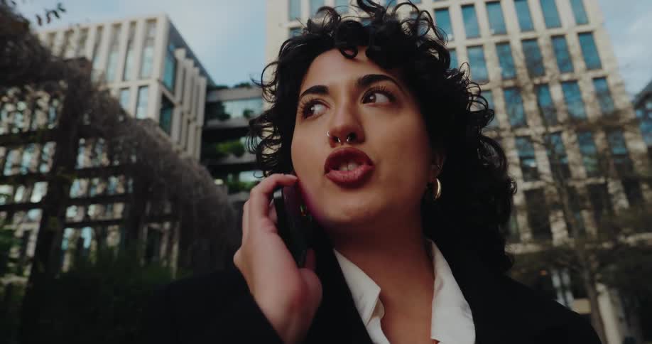Woman talking on the phone in an urban area surrounded by modern buildings